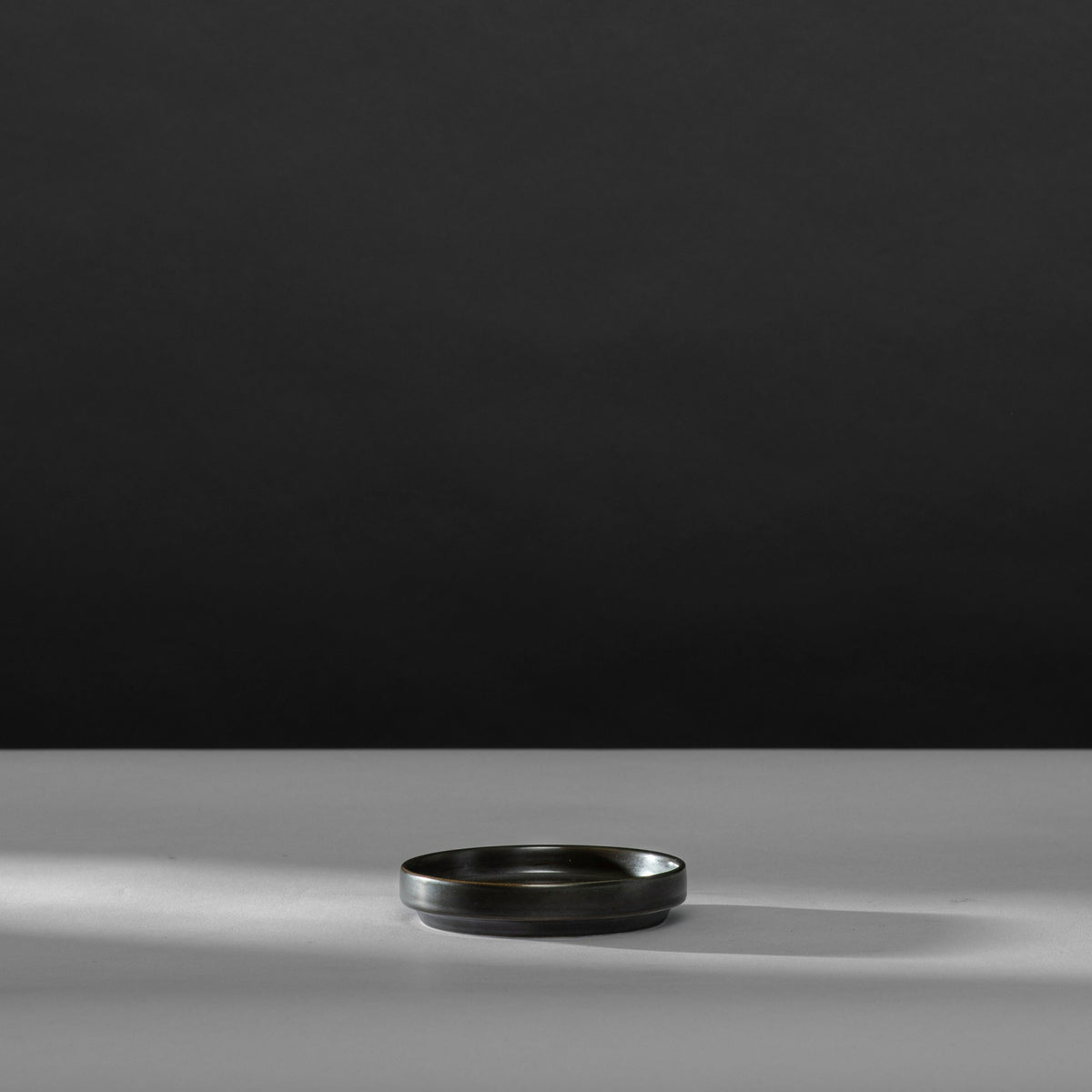 Schwarzes, rundes Tablett auf hellgrauer Oberfläche, minimalistisch und elegant.