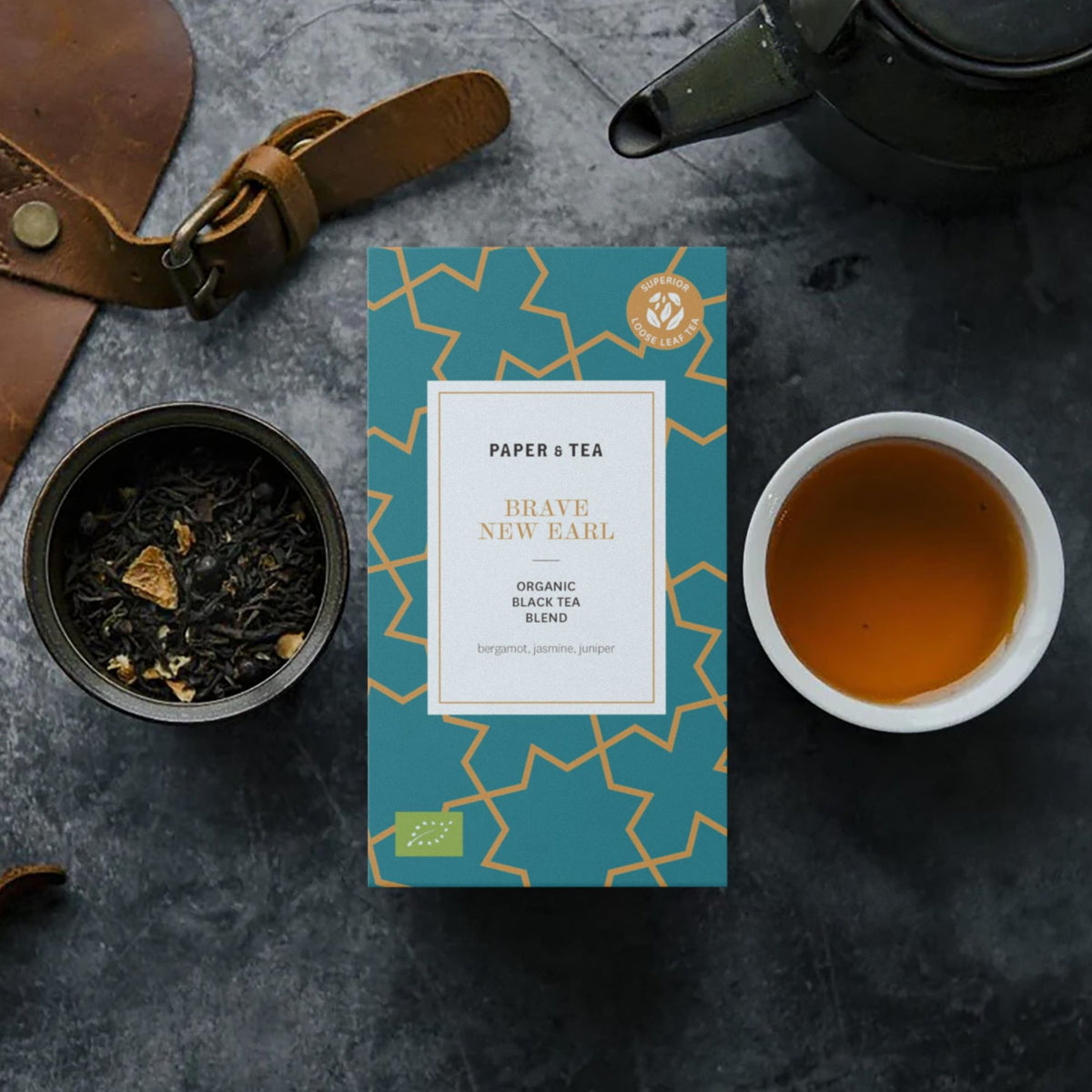 Kasten organischer BRAVE NEW EARL Schwarztee von PAPER & TEA mit Bergamotte, lose Blätter und Tasse Tee.