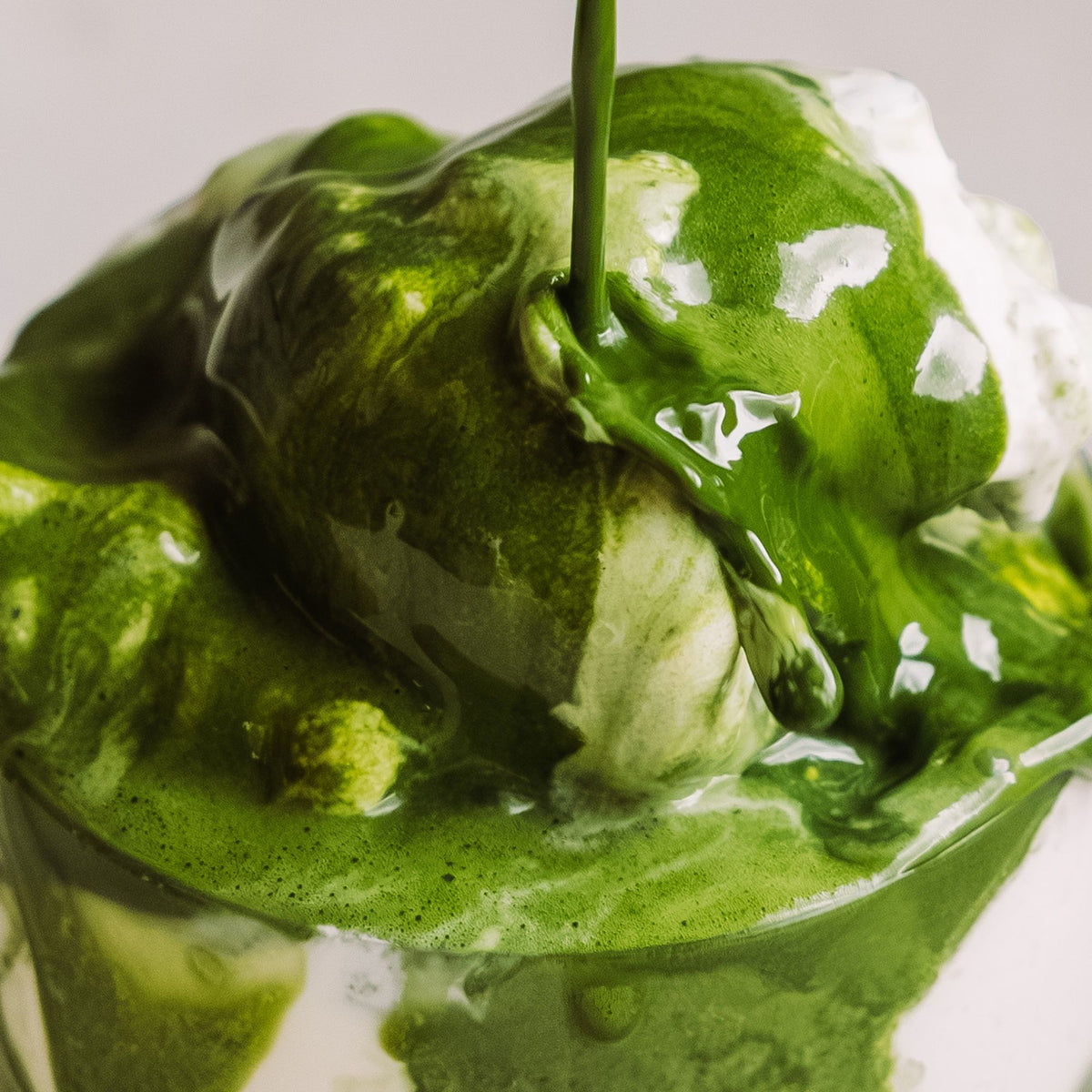 Vanilleeis mit dicker Matcha-Grünteesauce, die über das Eis fließt.