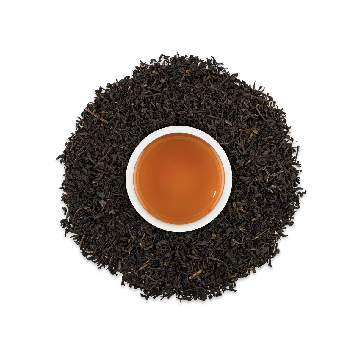 Weiße Tasse mit bernsteinfarbenem Schwarztee, umgeben von losem Schwarztee auf schwarzem Hintergrund.