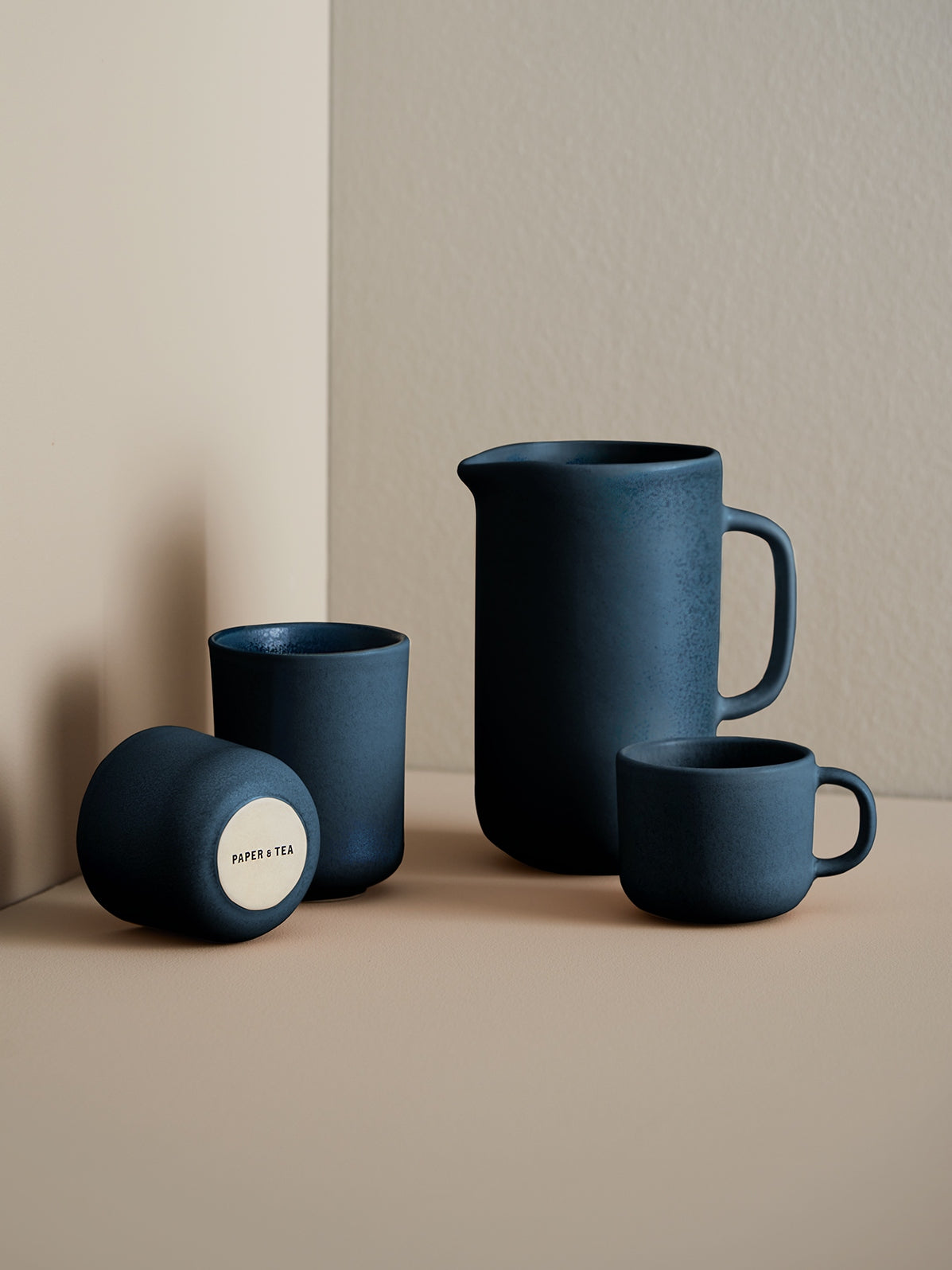 Minimalistische Keramikkomposition: Krug, Tasse und Becher von PAPER & TEA auf beigem Hintergrund.