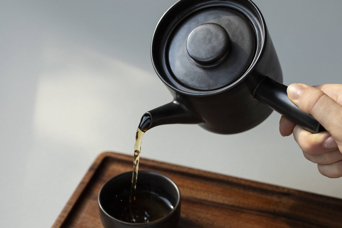 Schwarzer Kyusu und Tasse auf Holz-Tablett