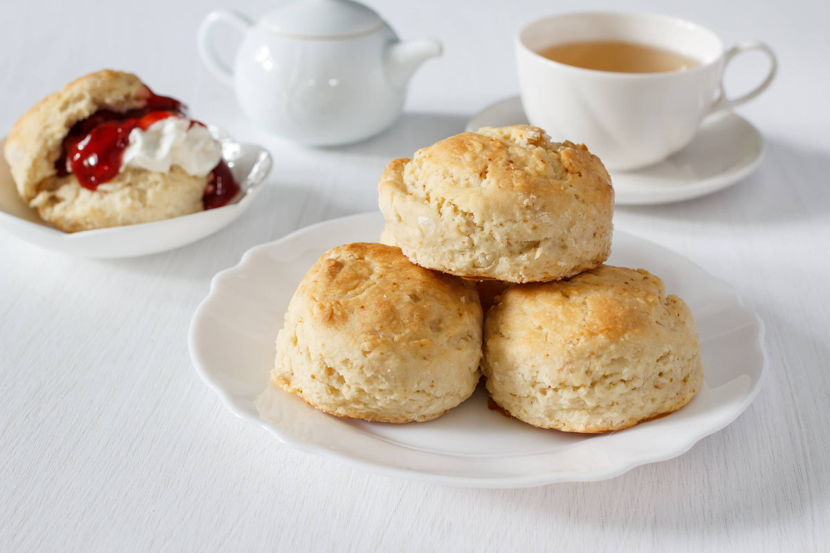 Frisch gebackene Scones auf Teller mit Tee im Hintergrund für britische Tea Time