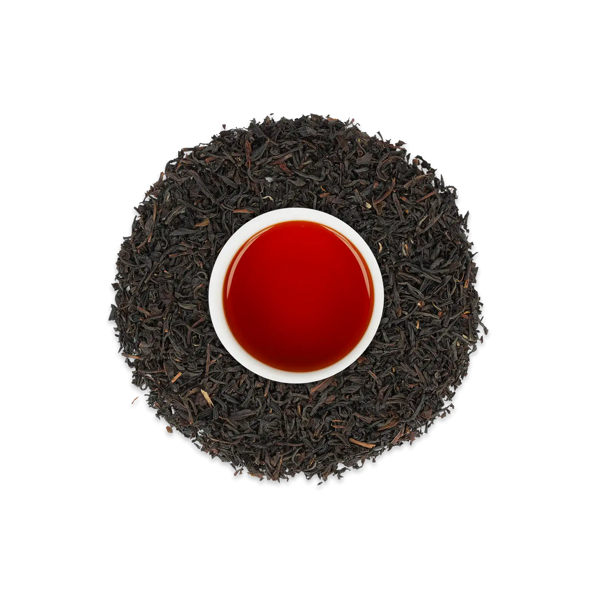 Weiße Keramiktasse mit rötlich-braunem Tee, umgeben von losem schwarzem Tee auf weißem Hintergrund.