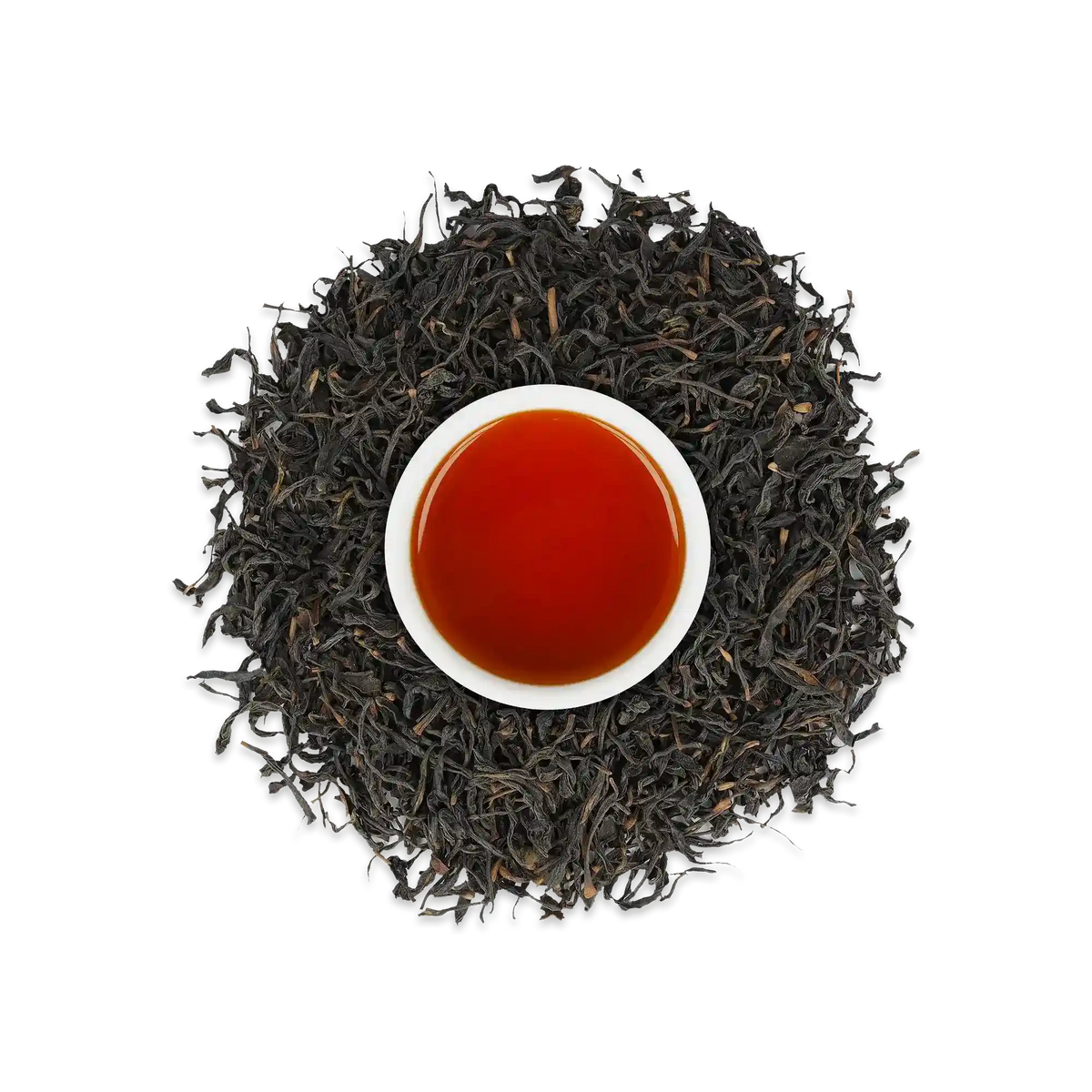 Weißer Becher mit dunkelbernsteinfarbenem Tee, umgeben von losen schwarzen Teeblättern, symbolisiert Schwarztee-Genuss.