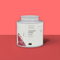 Weißer zylindrischer Teebehälter mit goldenem Earl Black Tea Design und rotem Pinselstrich vor rotem Hintergrund.