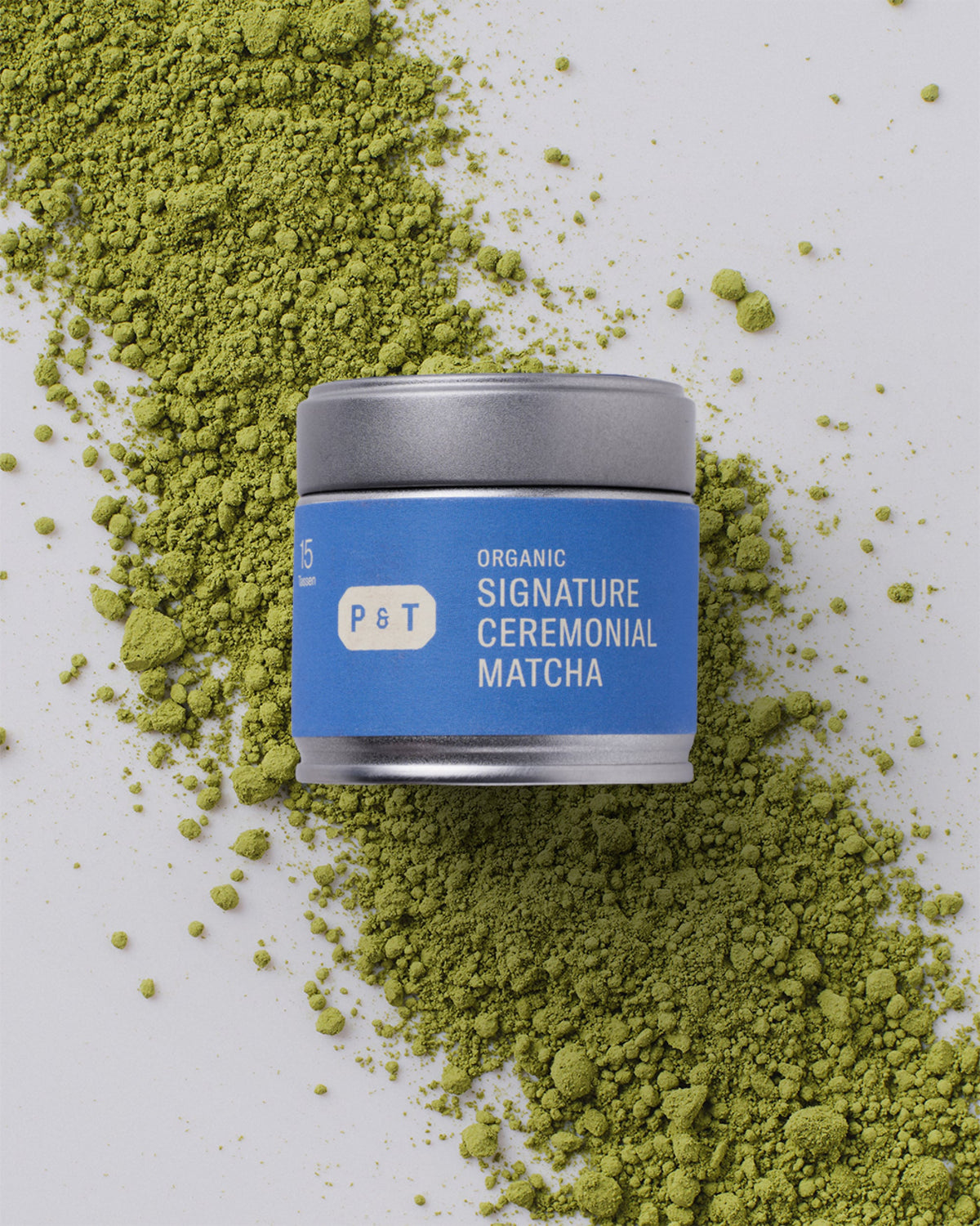 Kleiner Metallbehälter mit blauem Etikett. Aufschrift: 'P&T Organic Signature Ceremonial Matcha'. Mit grünem Matcha-Pulver.