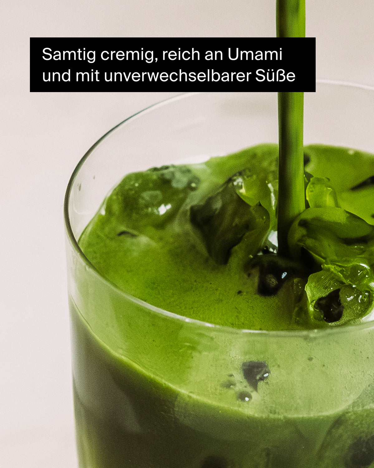 Glas mit cremigem Matcha-Getränk, umgeben von Eiswürfeln.